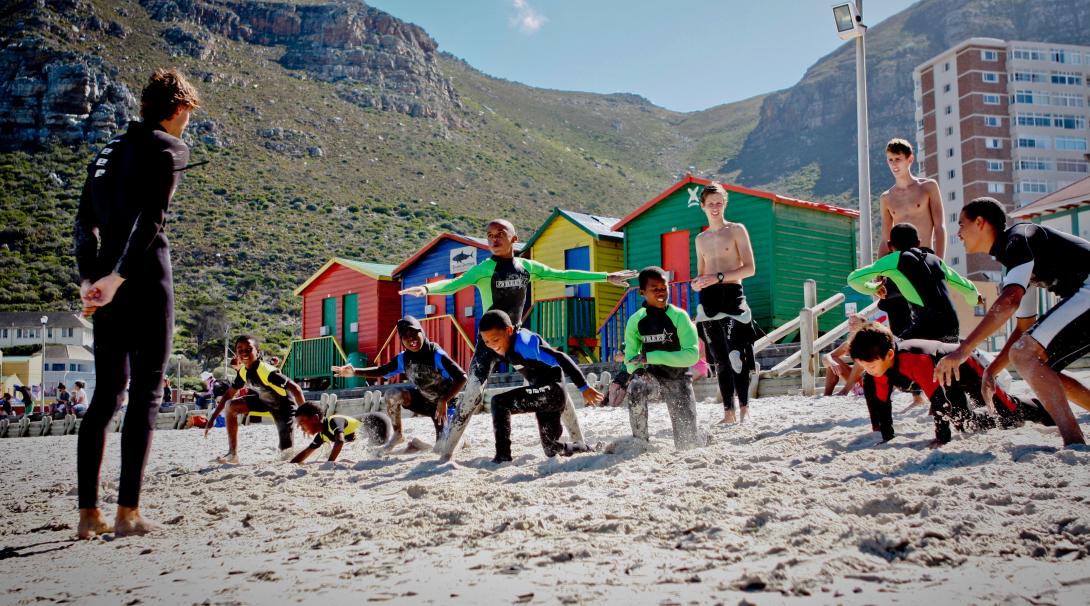 Volunteer getting children ready for surfing in South Africa Stretching on the beach in a surfing project, South Africa